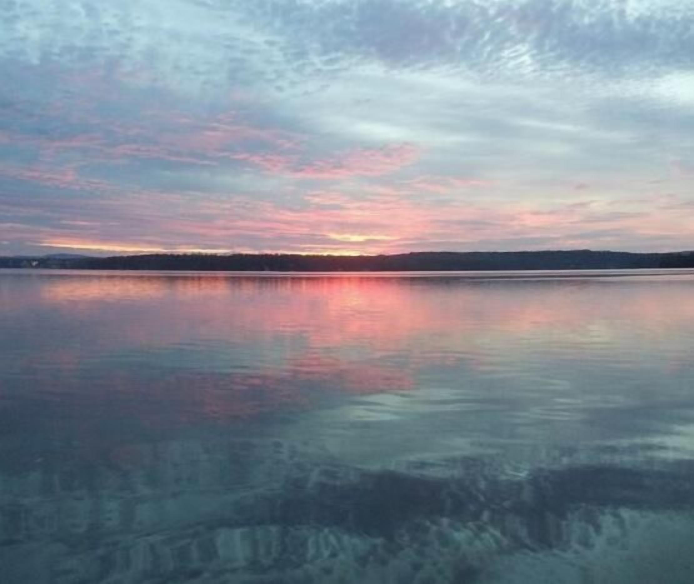 Une étendue d'eau calme qui reflète le ciel au coucher du soleil.