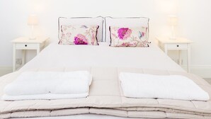 A neatly made bed with two pillows, two bedside tables with lamps, and a white wall. - City Centre Penthouse - New Street (Birmingham)