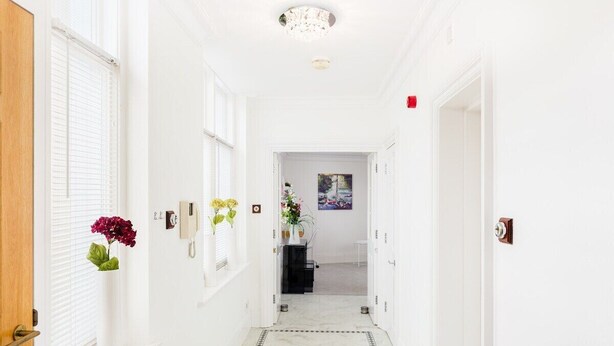 A hallway with white walls, a marble floor, and a door on the left. - City Centre Penthouse - New Street (Birmingham)