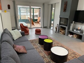 Uma sala de estar moderna com um sofá cinzento, um tapete estampado e uma TV de tela plana.