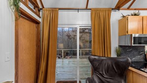 Una habitación con puerta corrediza de vidrio que da a un balcón, un sillón de cuero negro, armarios de madera y una encimera de mármol.