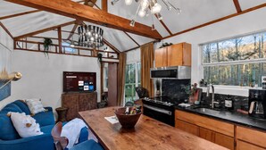 Una cocina moderna con una mesa de madera, un sofá azul y un televisor que muestra servicios de transmisión.