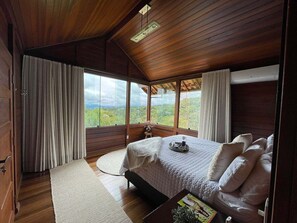 Ein Schlafzimmer mit einem großen Bett, Holzwänden und Blick ins Freie.