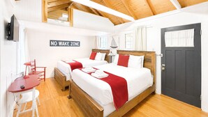 Une chambre avec deux lits, un bureau, une chaise, un panneau indiquant « INTERDICTION DE FAIRE DU BRUIT » et une porte sombre.