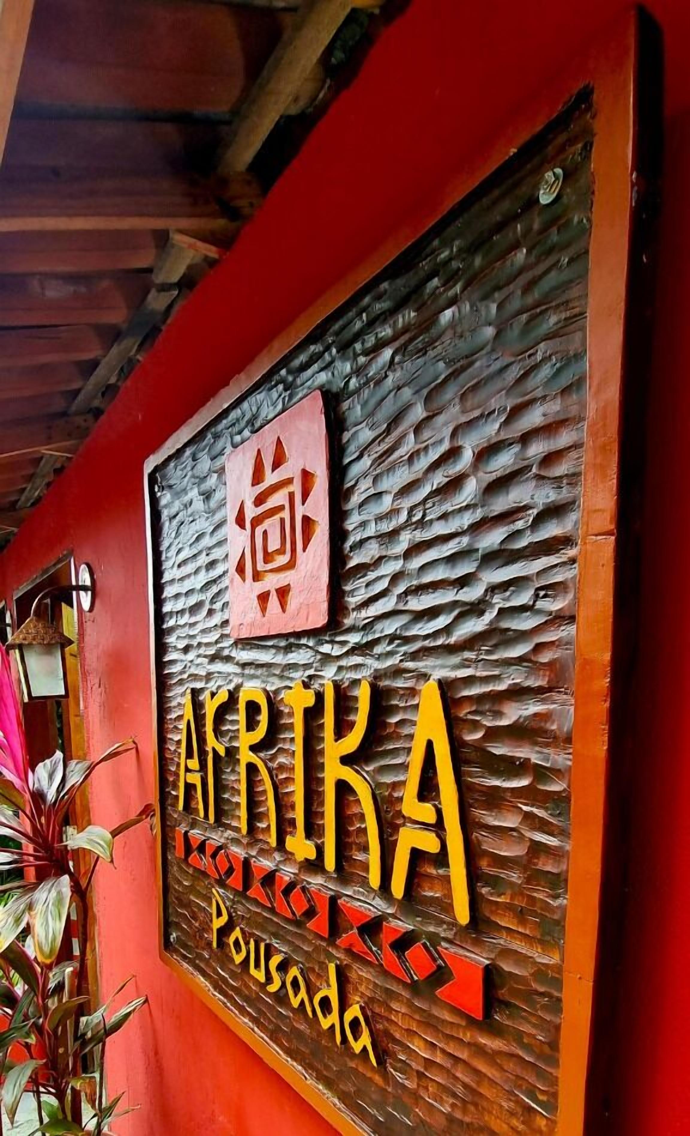A wooden sign with the name "AFRIKA Pousada" and decorative elements.