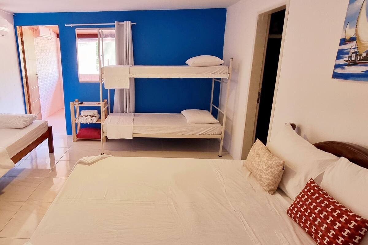 A room with bunk beds, a single bed, and a painting on the wall.