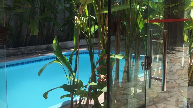 A glass-enclosed pool area with a clear view of the pool and surrounding greenery. - Pousada Afrika (Ipojuca)