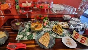 A buffet table with various food items and utensils. - Pousada Afrika (Ipojuca)