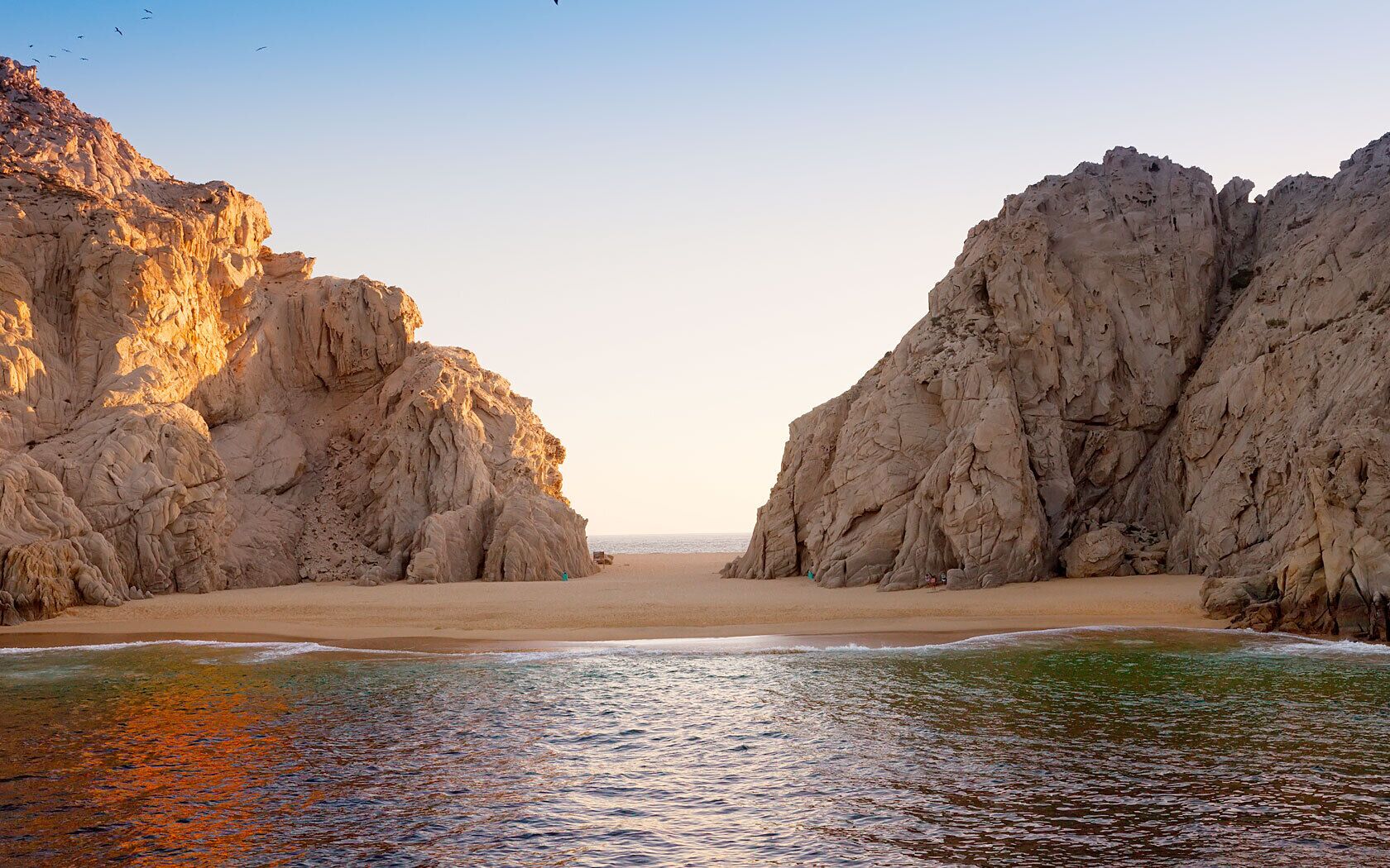 Un paysage côtier caractérisé par des falaises rocheuses et une plage de sable.