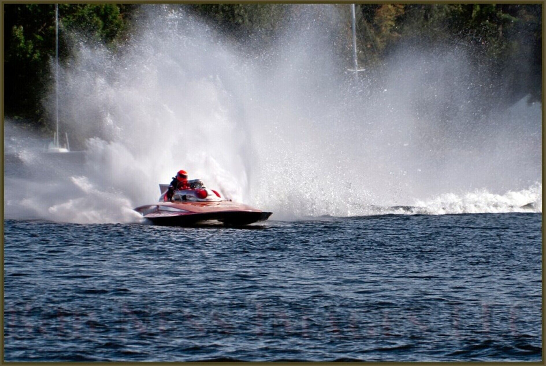 A speedboat creating a large water spray on a lake.