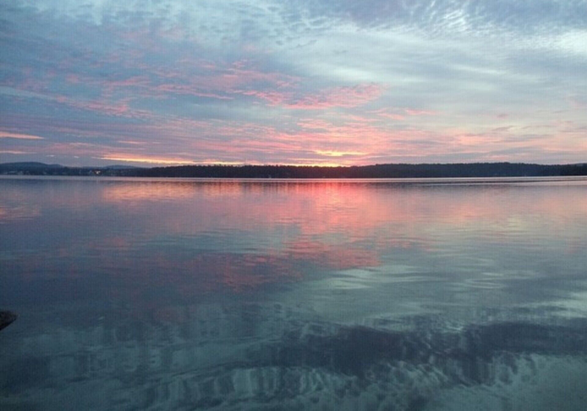 Un lac paisible au coucher du soleil, sous un ciel dégagé.
