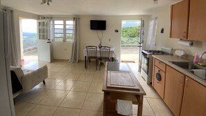 Cucina con zona pranzo, TV a parete e vista sull'esterno.