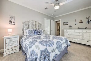 Ein Schlafzimmer mit einem großen Bett, einem Nachttisch, einer Kommode und einem Deckenventilator.