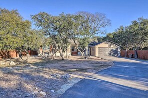 A single-story house with a garage, surrounded by trees and a clear sky.