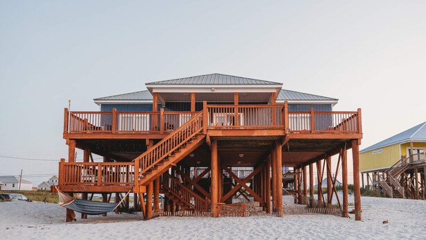 Una casa de playa de madera con balcón y escaleras.