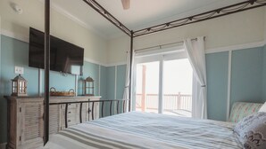 Un dormitorio con cama con dosel, un televisor montado en la pared y un balcón con vistas.