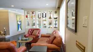Un salon avec des canapés en cuir, une table basse et une vitrine contenant des objets décoratifs.