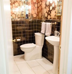 Un baño con inodoro, lavabo y papel tapiz decorativo con motivos florales.