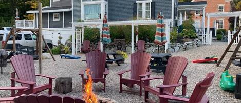 A patio area with Adirondack chairs, a fire pit, and a covered seating area with umbrellas.