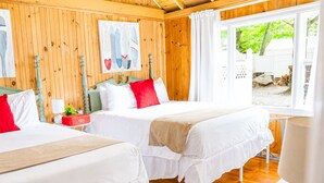 Une chambre avec deux lits, des murs en bois, une fenêtre avec des rideaux et un tableau accroché au mur.