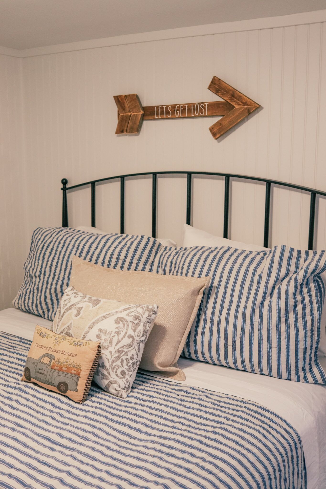 A bed with striped bedding and a pillow with a floral pattern.