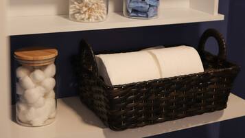 A bathroom with a white cabinet, a shower curtain, and two jars on the shelf.