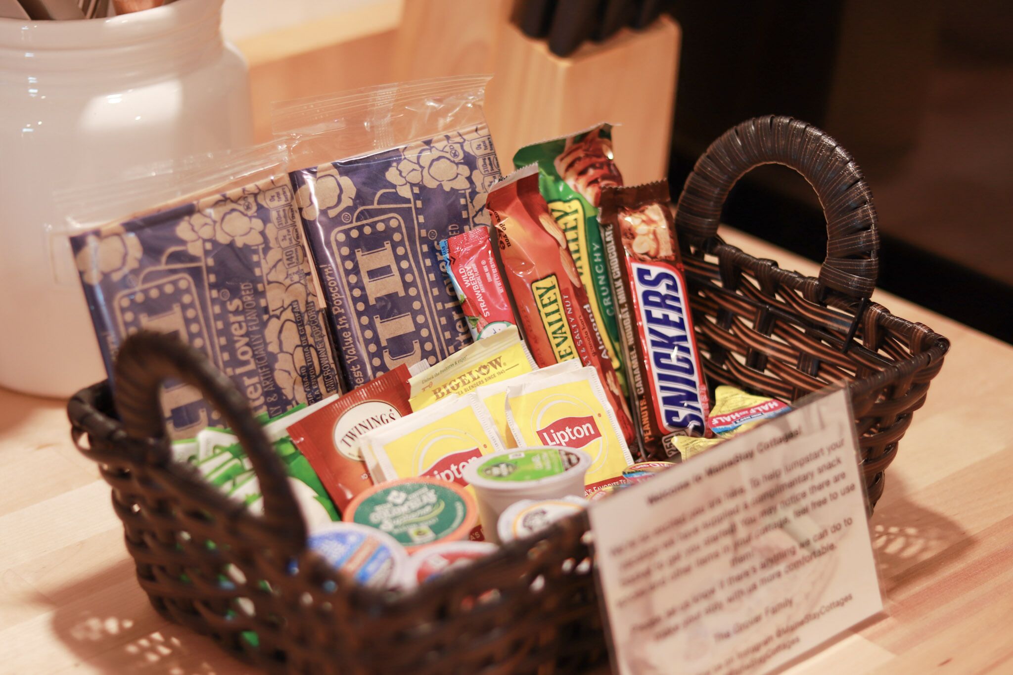 En kurv fyldt med forskellige pakker med snacks og et skilt med instruktioner.