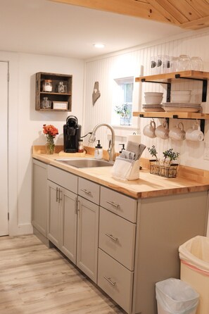 A kitchen with a wooden countertop, a sink, cabinets, and a trash bin. - NEW MaineStay Cottage #3 Full Kitchen + Fireplace in Hampden/Bangor (Hampden)