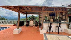 Un espace extérieur abrité avec des places assises, un bar, des meubles en bois et une vue sur les montagnes.