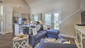 A spacious living room with a grey sectional sofa, a small round table, and a staircase leading to an upper level.