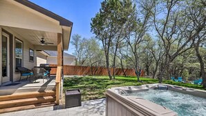 A backyard with a hot tub, patio furniture, and a wooden deck.