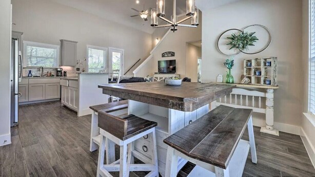 A spacious kitchen with a central island, bar stools, and a chandelier.