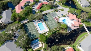 An aerial view of a residential area with a tennis court, swimming pool, and a dock. - JD-near Beaches and IMG, Pool, Tennis, Pickleball, Shorewalk condo 2 Bedroom/2 Bath lake view (Bradenton)