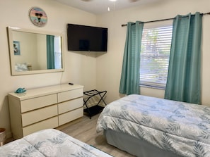 A bedroom with a bed, a dresser, a TV, a window with curtains, and a mirror. - JD-near Beaches and IMG, Pool, Tennis, Pickleball, Shorewalk condo 2 Bedroom/2 Bath lake view (Bradenton)
