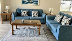 Uma sala de estar com um sofá azul, uma mesa de centro de madeira e um tapete.