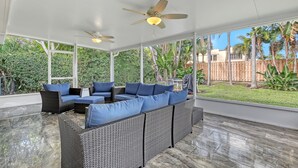 A covered outdoor seating area with wicker furniture and ceiling fans. - Beach House just steps from Sun & Fun! (North Palm Beach)