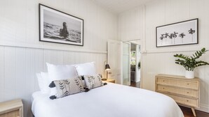 A bedroom with a bed, a nightstand, a dresser, and two framed pictures on the wall. - High Three - Charming Beachside Retreat in the Heart of Yamba - Holiday Yamba (Yamba)