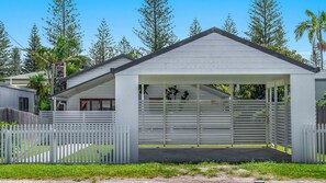 A single-story building with a covered porch and a white fence.