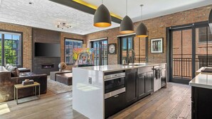 A modern kitchen with a central island, black cabinetry, and stainless steel appliances.