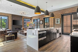 A modern kitchen with a central island, black cabinetry, and stainless steel appliances.