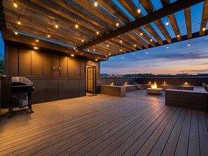 An outdoor deck with a wooden floor, built-in seating, a grill, and string lights. - Nashville WeHo Escape | Walk to Bars & Dining (Nashville)
