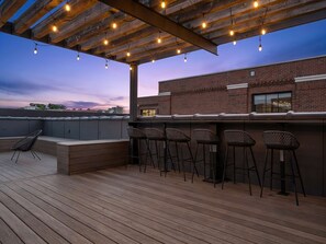 An outdoor deck with a bar area, seating, and a view of the city skyline. - Nashville WeHo Escape | Walk to Bars & Dining (Nashville)