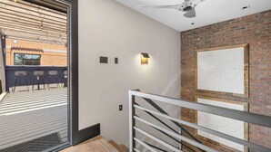 A modern interior with a ceiling fan, a brick wall, and a staircase with metal railings.