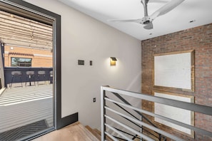 A modern interior with a ceiling fan, a brick wall, and a staircase with metal railings.
