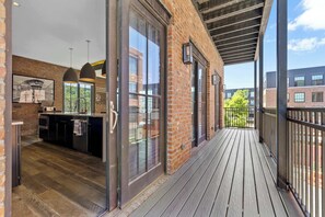 Un balcón con piso de madera y vista a un edificio de ladrillo.