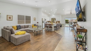 A spacious living area with a sofa, ottoman, and dining table.