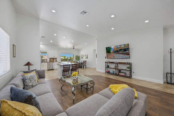 A spacious living area with a sofa, coffee table, and a painting on the wall.