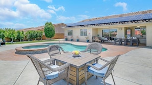 A patio with a pool, outdoor furniture, and a building with solar panels.