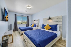 Et hotelværelse med to senge, et fjernsyn, et vindue med gardiner, et sengebord og en træsenggavl.