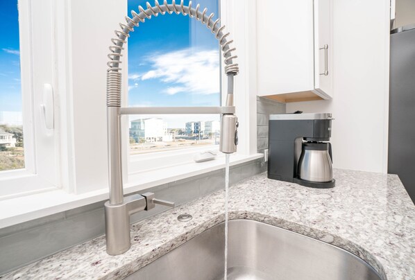 Una cocina moderna con un lavamanos de acero inoxidable, hervidor integrado y ventana con vista a la ciudad.